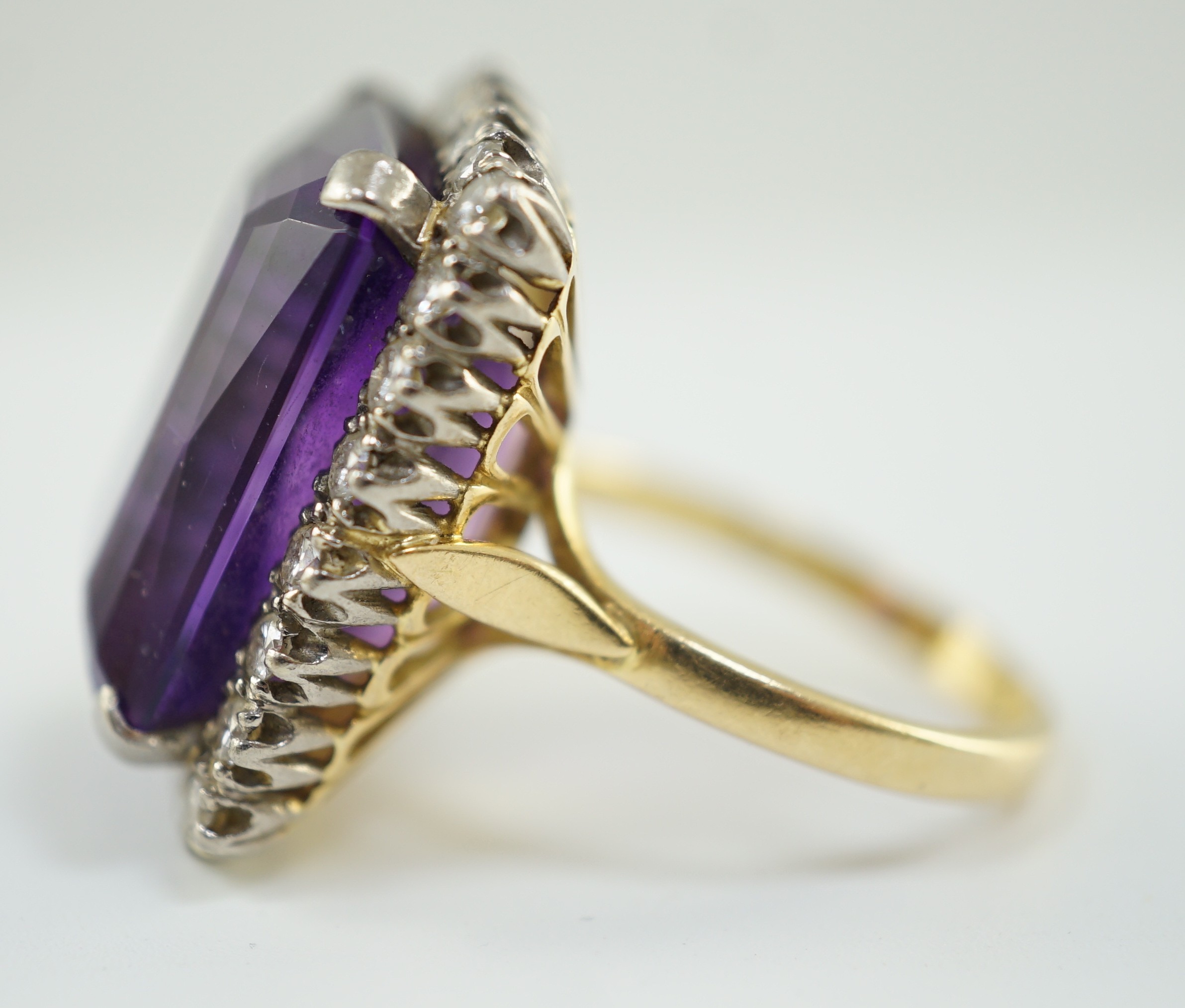 A large modern 18ct gold and emerald cut amethyst set dress ring, with diamond set border